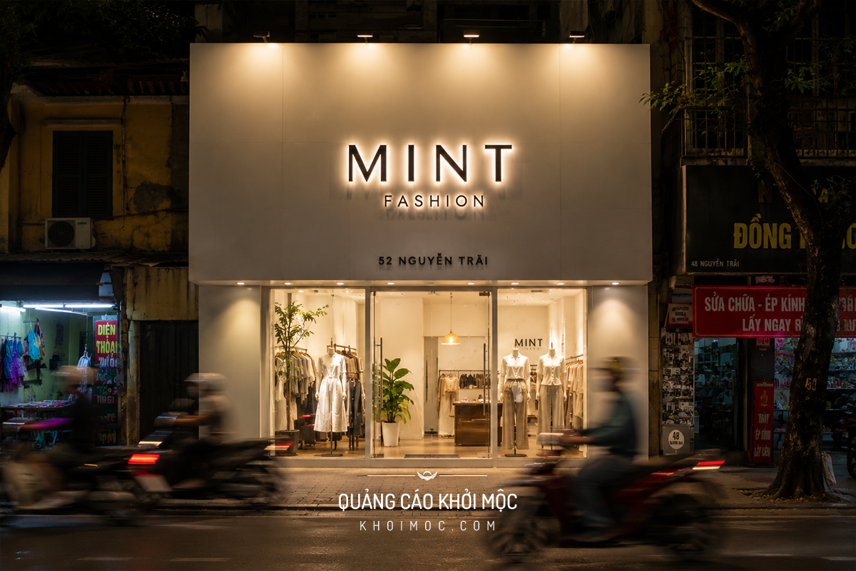Mặt tiền shop thời trang nhỏ lên đèn buổi tối nhìn từ vỉa hè