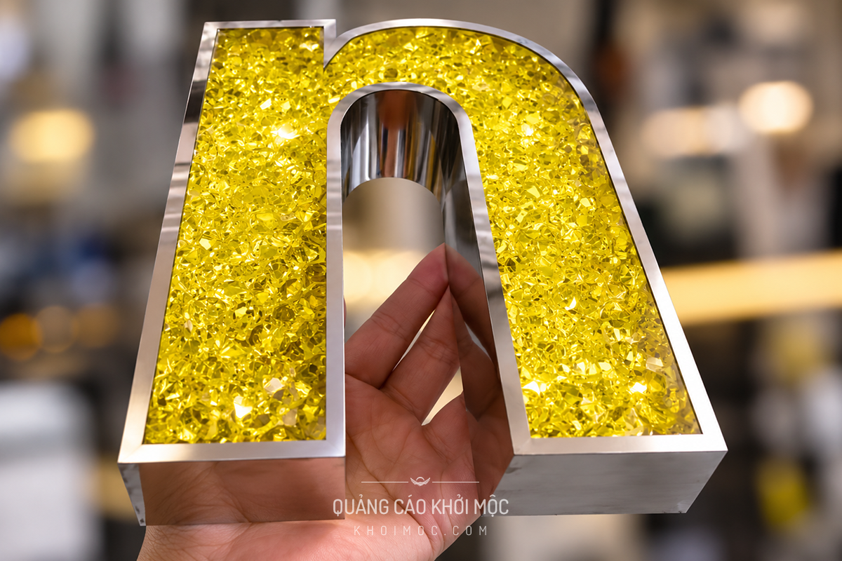 Cận cảnh hạt nhựa acrylic giả đá bên trong chữ inox ánh vàng
