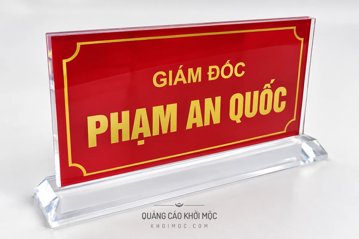Ảnh minh họa kệ mica chức danh đế khối liền, nền đỏ chữ vàng viền hoa văn